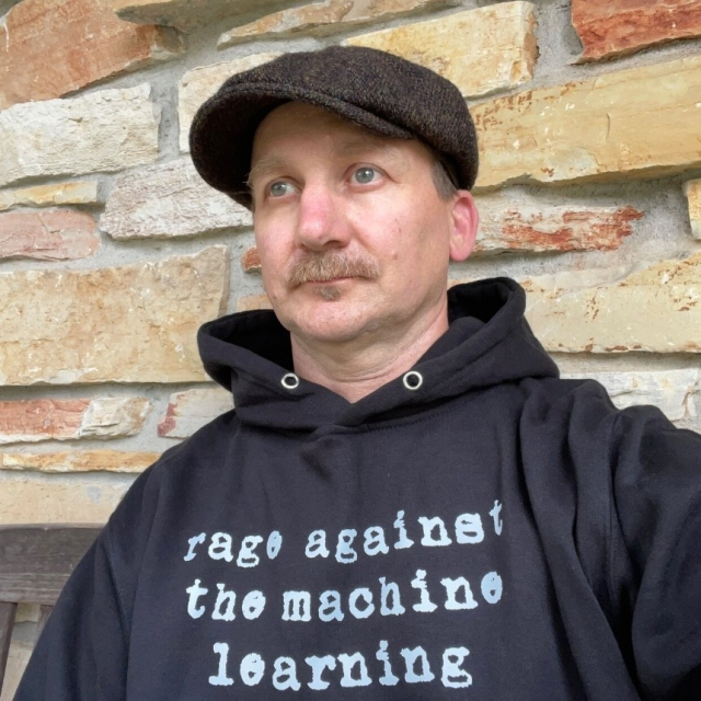 Man wearing a hoody with text. The text says: rage against the machine learning