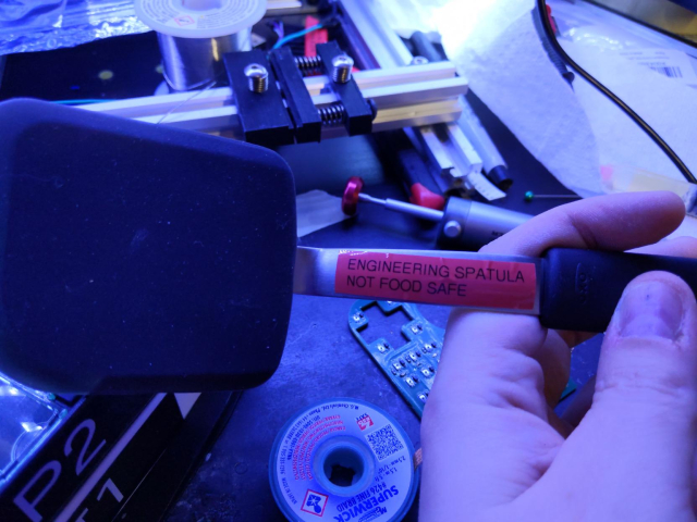 silicone spatula with a red label on its handle, reading "engineering spatula, not food safe" in all caps