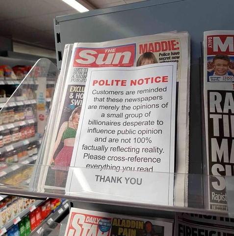 The Sun "newspaper" on sale in a supermarket. Somebody has added a sheet of paper in front of the scurrilous rag, with the message
"Polite notice
Customers are reminded that these newspapers are merely the opinions of a small group of billionaires desperate to influence public opinion and are not 100% factually reflecting reality. Please cross-reference everything you read.
Thank you."