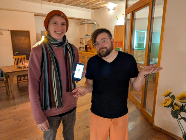 Caleb holding a Pixel 3 phone running PostmarketOS standing next to me shrugging