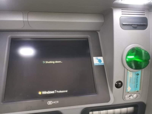 Photo of an ATM machine with a Windows 7 Professional Shutting down screen.