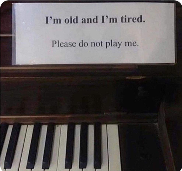 A piano with a sign that says: I'm old and I'm tired. Please do not play me.