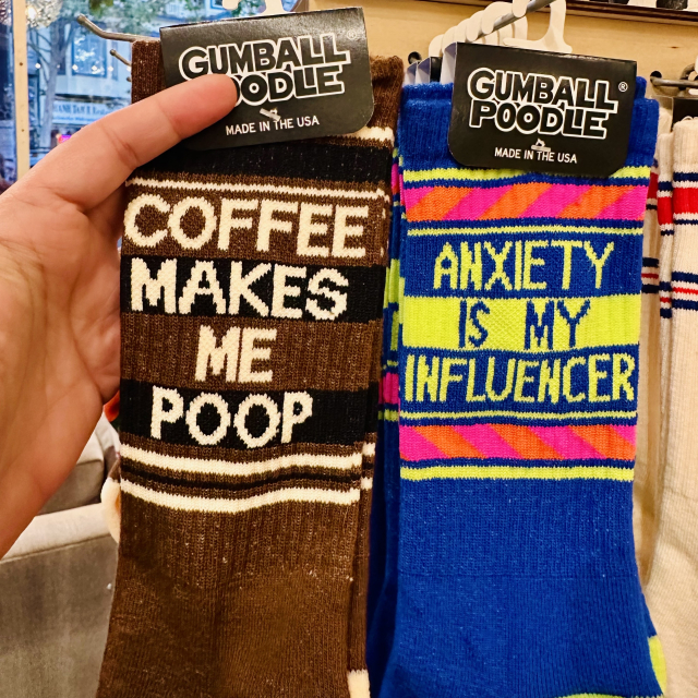 A photo of 2 pairs
of socks. One says Coffee Makes Me Poop

The other says Anxiety is my Influencer