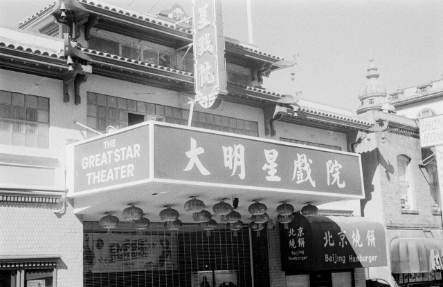 a scan of a 35mm black and white film photo of a theater in SF Chinatown with Chinese characters