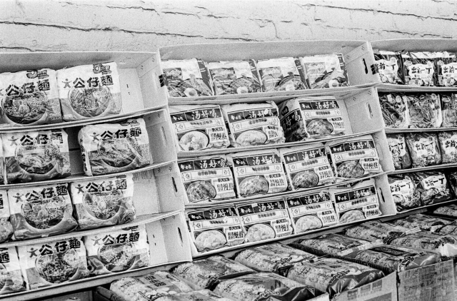 a scan of a 35mm black and white film photo of instant noodles for sale in SF Chinatown