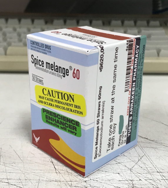 A photo of a blue & white box of Spice melange 60, containing 60mg of Geonemotodium arraknis, prescribed to co-worker craig. It's a pretty mundane looking medication box, with a sand dune on it, and an atreides logo - along with a bunch of stickers warning it may cause permanent iris and sclera discolouration, and that it's a prescience enhancer.