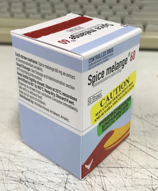 A photo of a blue & white box of Spice melange 60, containing 60mg of Geonemotodium arraknis, prescribed to co-worker craig. It's a pretty mundane looking medication box, with a sand dune on it, and an atreides logo - along with a bunch of stickers warning it may cause permanent iris and sclera discolouration, and that it's a prescience enhancer.