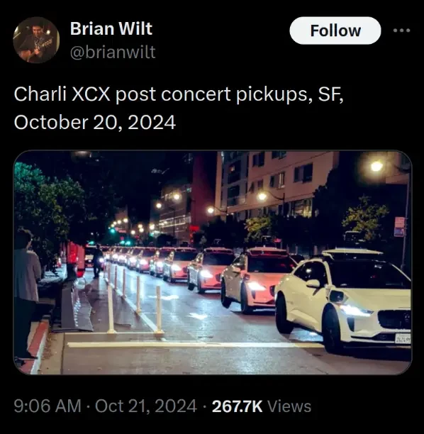 Post on X by Brian Wilt:
"Charli XCX post concert pickups, SF, October 20, 2024"

A row of identical white cars with black spinning sensors on the top stretches down a block as far as the eye can see. There is also one further down that appears to block the bike lane.