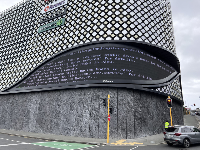 A large digital advertising sign showing Linux boot messages 