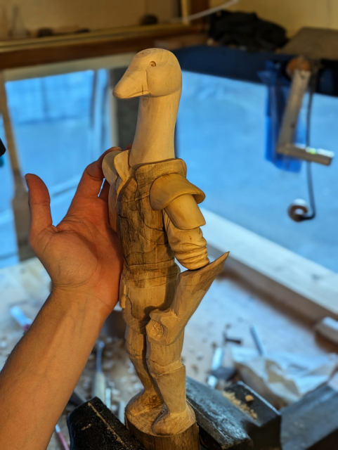 Draft of a woodcarved humanoid goose wearing plate armour