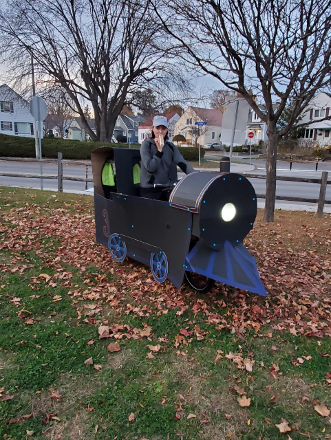 Me and my cargo bike decorated with cardboard to look like a steam train complete with a headlight, smoke stack, and cow catcher 