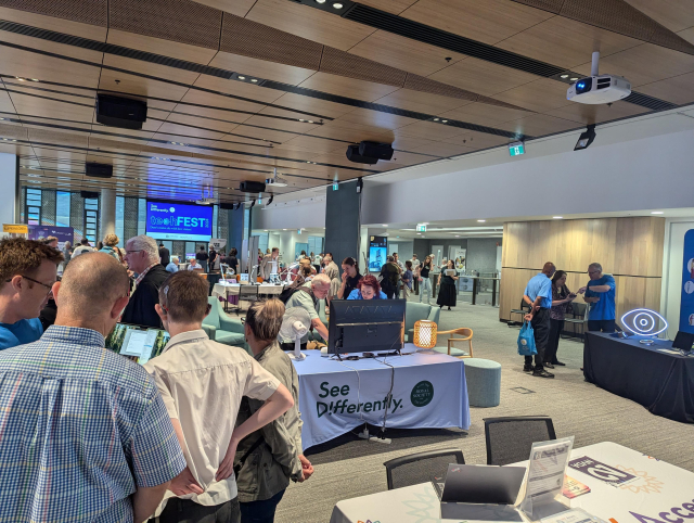 A large room with tables of exhibits and people showing off different products. A table with NVDA displays in the foreground.