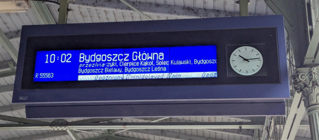 A departure board showing train R55563 to Bydgoszcz Glowna with scheduled departure of 10:02 delayed by 17 minutes.