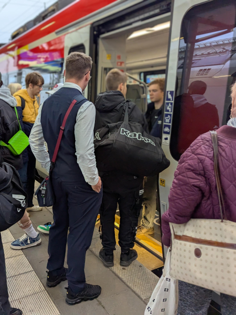 A crowd waiting to board the train. One person is standing in the door opening.