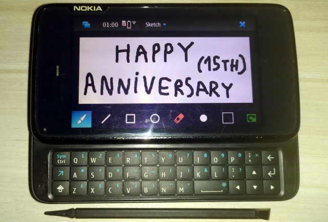 A picture of the Nokia N900 with the Sketch app running, the drawing on the screen says "HAPPY (15th) ANNIVERSARY"