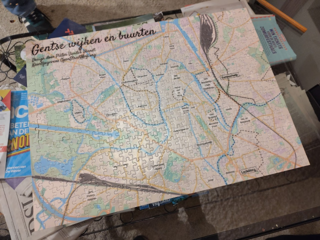 A completed jigsaw puzzle featuring a detailed map of Ghent, labeled "Gentse wijken en buurten" (Ghent neighborhoods and districts), created by Pieter Vander Vennet using OpenStreetMap data. 