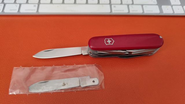 Swiss Champion knife, open and showing the large blade, alongside the original broken blade in a plastic bag.