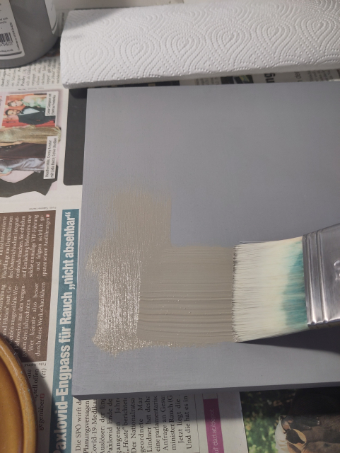 A grey panel is being painted with a slighty different grey and a large brush.