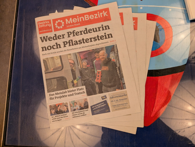 Mehrere Zeitungen liegen auf einem Glastisch. Sie heißen "MeinBezirk", auf dem Titelblatt sind mehrere Menschen stehen neben einer Telefonzelle. Eine Person schaut daraus hervor.
Der Artikel dazu ist mit "Das Metalab bietet Platz für Projekte und Tratsch".
