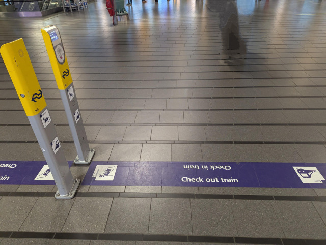 A sticker on the floor between OV chipkaart poles.

On the sticker, "Check out train" is readable while "Check in train" is upside down.