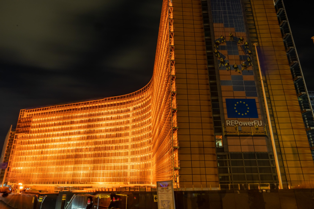 The image depicts the Berlaymont building, the headquarters of the European Commission in Brussels, illuminated in vibrant orange. This striking display is part of the Orange the World campaign, a global initiative to raise awareness and call for an end to violence against women and girls.