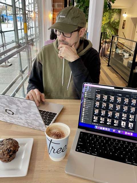 White male sitting in a coffee shop working at the computer, coffe and muffin in the table