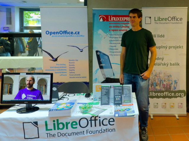 Photo of booth attendee at LibreOffice booth with banners and merchandise