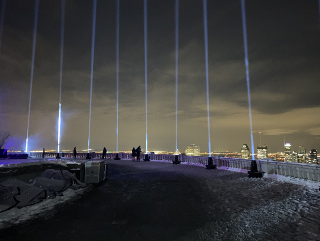 14 beams of light going into the sky. Montréal in the background.