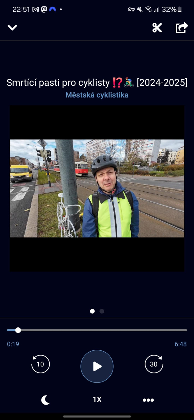 A podcast episode with a video content in a podcast app. There is a guy in a bike helmet and yellow jacket standing by a road in the video.