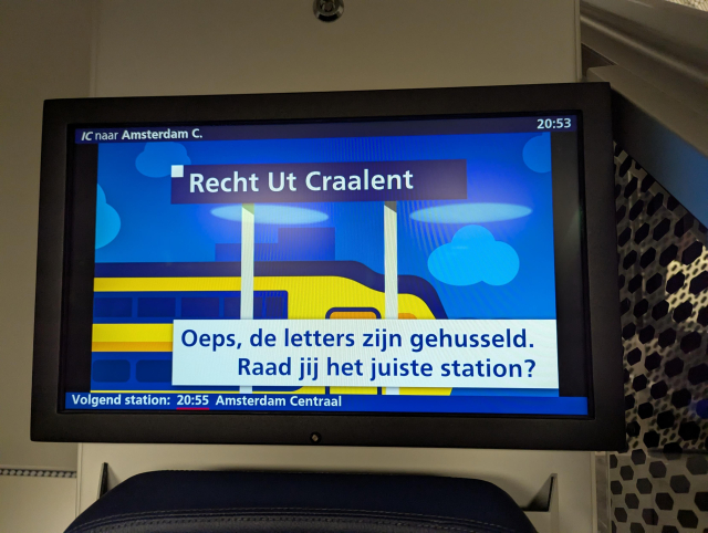 A picture of an onboard information screen showing a letter puzzle with text "Recht Ut Craalent" representing the name of a train station.