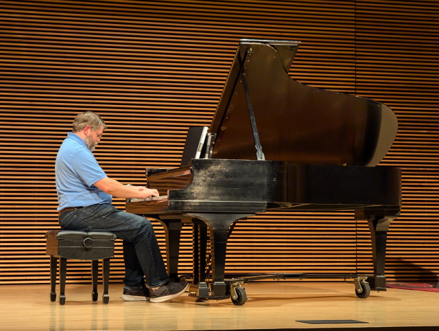Jonathan on stage seated at a baby grand piano