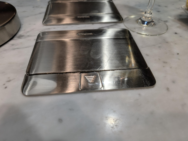 A marble-effect tabletop with a flush mounted rectangular silver object. A sliding eject button is visible at the closest edge of the object.