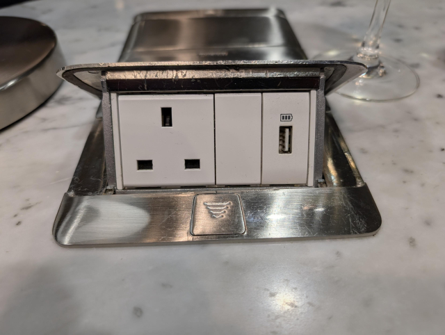 The same object, now open - it has hinged along the farthest surface to reveal a UK-style plug socket and a USB-A port