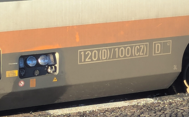 A side view of a Diesel multiple unit train in Trilex colour scheme. On the left there are tanking inlets, on the right there's a speed limit written as 120 (D) / 100 (CZ)