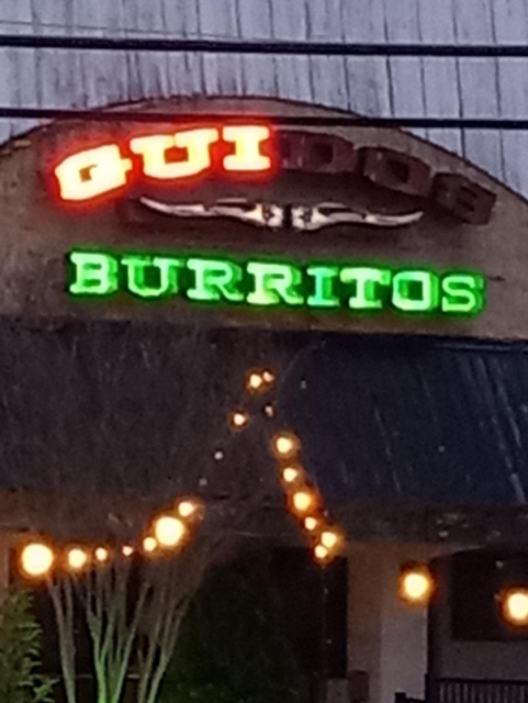 "GUI Burritos"
spelled out on a neon sign for Guido's Burritos, with some lights out.