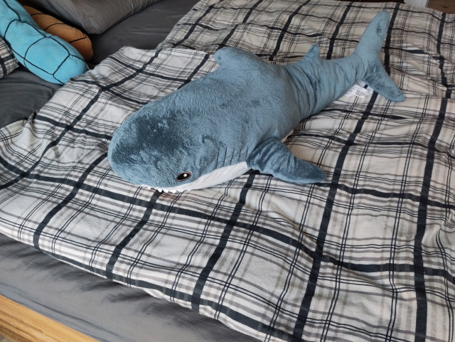 A blåhaj lying on a bed.