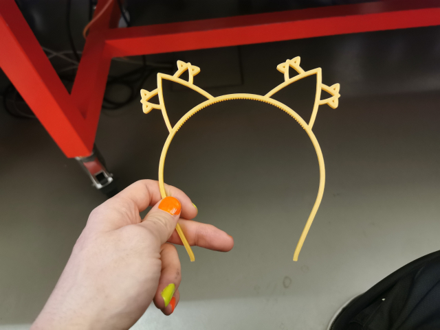 A hand holding 3D printed cat ears but the cat ears have smaller cat ears which have even smaller cat ears
