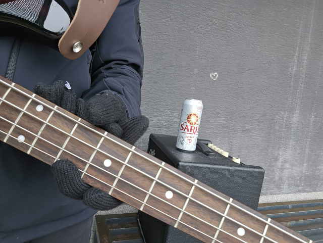 mnou držiac 4 strunová bass gitara zo záberom na pražce, v pozadí kombo a na kombe Šariš desina, na autobusovej zastávke 