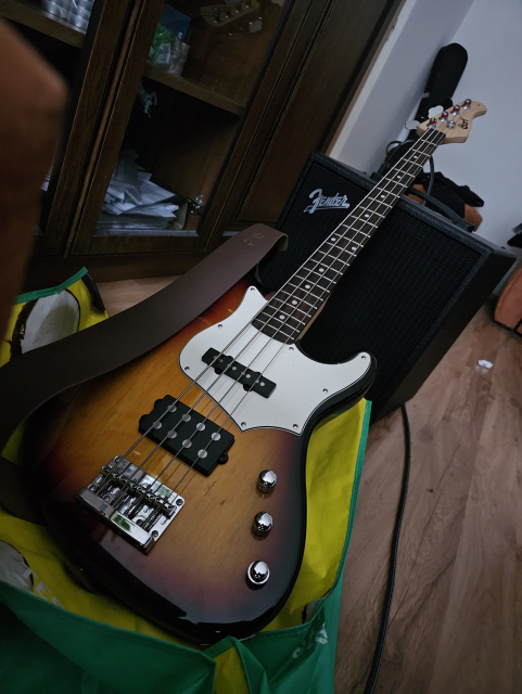 basová gitara opretá o kombo, drevená podlaha, v ľavo drevená presklenná skrinka