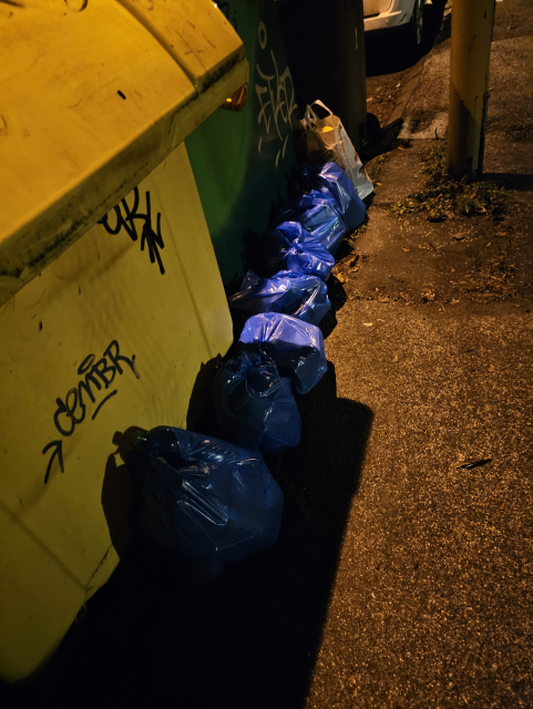 modré pytle vedľa kontajnerov s plechovkami a fľašami