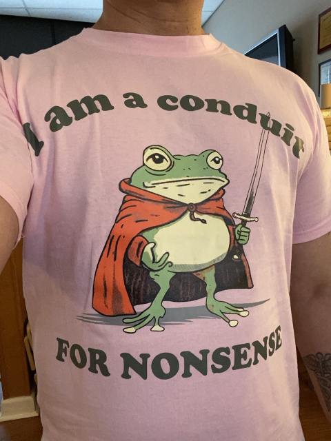 pink T-shirt, with a drawing of a frog wearing a red cape, standing on his hind legs, carrying a sword and the caption says I am a conduit for nonsense