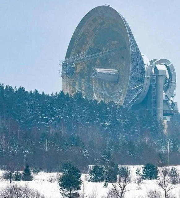 picture of a giant radar dish behind a forest