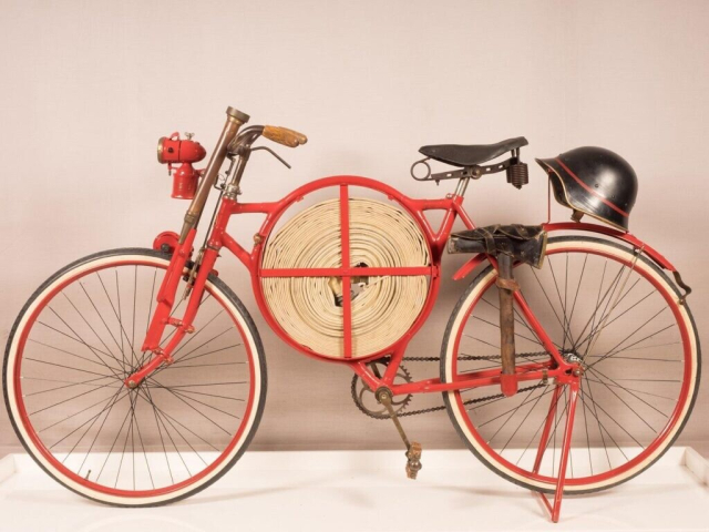 Firefighter bike equiped with, fire hose, axe, crowbar, helmet, headlamp and friction siren at the fron. Model circa 1905.