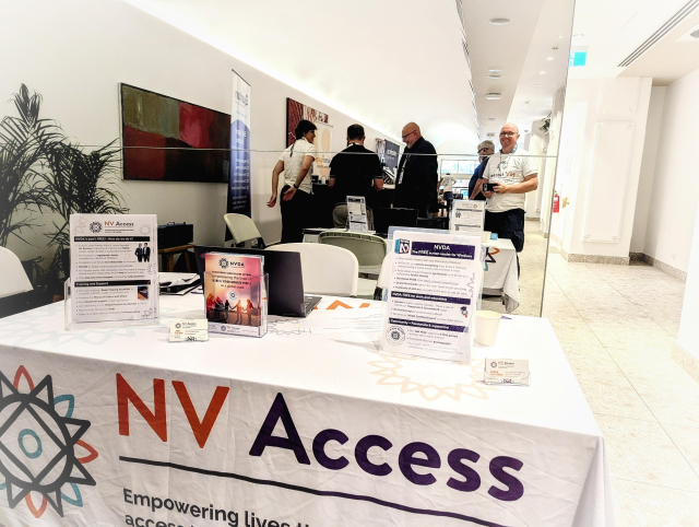 A table with NV Access tablecloth, brochures and a laptop to demonstrate NVDA.