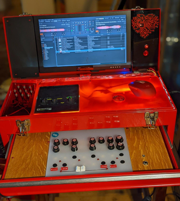 A red metal tool box, the lid open to reveal a monitor built into it displaying DJ software. The top drawer of the toolbox is also open to show a DJ midi controller built into it