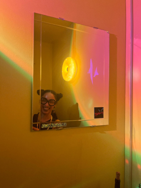 same femme dj in the booth but the reflection of their face is seen in a mirror