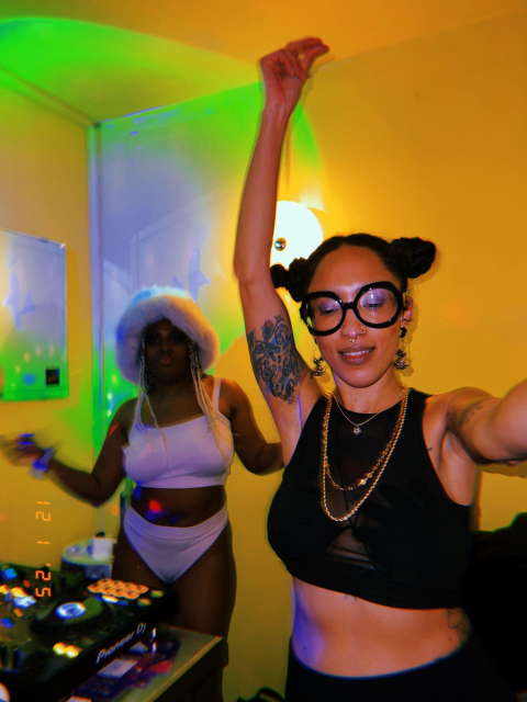 two femme dj's. one wearing a fuzzy purple hat and purple gogo outfit, me in the forefront dancing