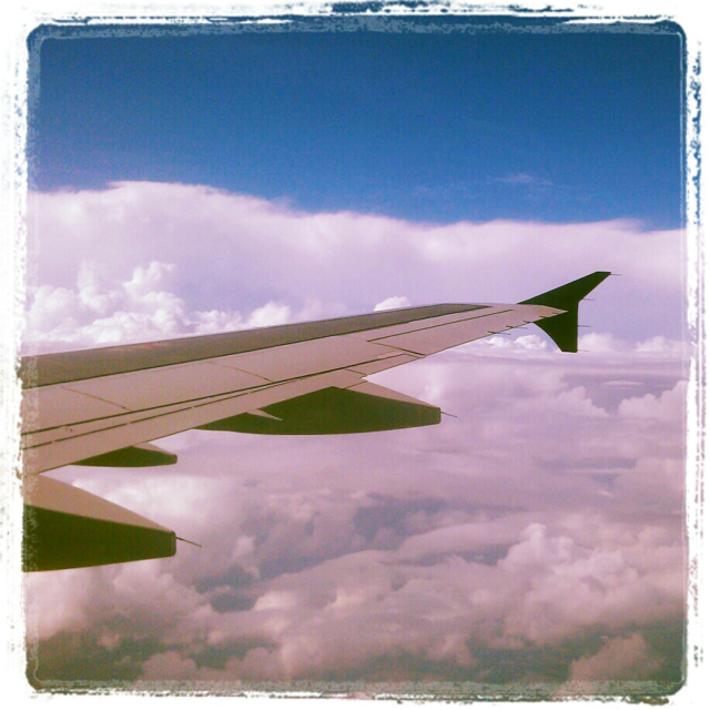 A square photo of a plane wing jutting out across a layer of clouds below a blue sky. The colors are badly tinted - with pinkish hues - and the edges of the photo spill into the white frame surrounding the photo. It's charmingly bad.

The flight was just bad. Six hours, cross-country, with no wifi and a broken video monitor embedded in the seatback in front of me.