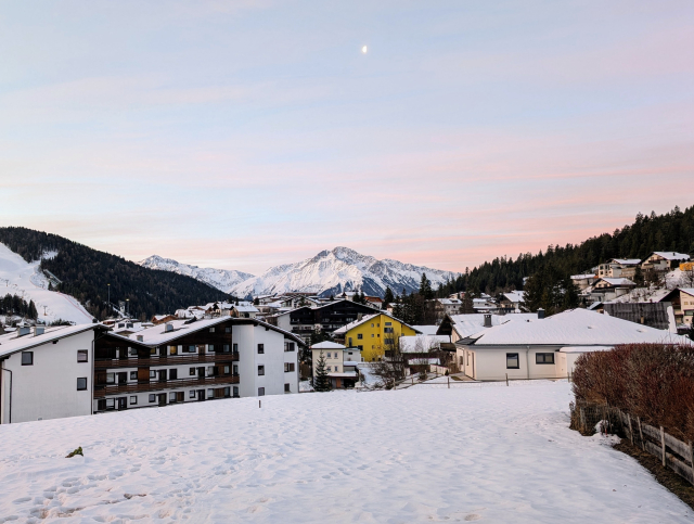 An alpine village with snowy mountains in the background. 