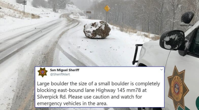 Tweet from San Miguel Sheriff (@SheriffAlert) superimposed on a photo of a snow-crusted boulder blocking the right lane of a snowy rural road.
Tweet: 
"Large boulder the size of a small boulder is completely blocking east-bound lane Highway 145 mm78 at Silverpick rd. Please use caution and watch for emergency vehicles in the area."